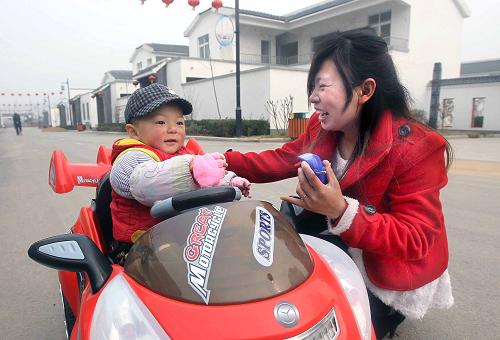 在河南省舞鋼市尹集鎮(zhèn)張莊社區(qū)內(nèi),一位村民帶著孩子在街道旁玩耍(2012年3月11日攝)。據(jù)近日舉行的河南省住房城鄉(xiāng)建設(shè)工作會(huì)上公布的數(shù)據(jù),至2012年年底,河南省城鎮(zhèn)化率達(dá)到42.2%,比上年提高1.8個(gè)百分點(diǎn)。全省新增城鎮(zhèn)人口180萬(wàn)人,帶動(dòng)城鎮(zhèn)固定資產(chǎn)投資1800億元以上。新華社記者 王頌 攝