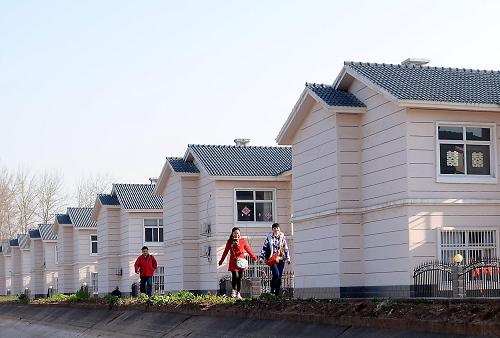 在河南省沁陽(yáng)市袁屯村社區(qū),幾位年輕人從連排式住宅旁走過(guò)(2012年3月24日攝)。新華社記者 王頌 攝