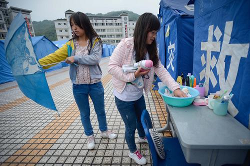 4月29日,在天全縣天全中學(xué),兩名學(xué)生在帳篷宿舍前整理洗漱用品。新華社記者 李橋橋 攝