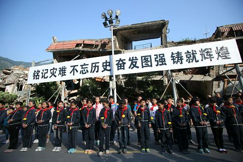5月12日,在北川老縣城地震遺址,小學(xué)生手拿菊花祭奠地震遇難者。新華社記者 王申 攝