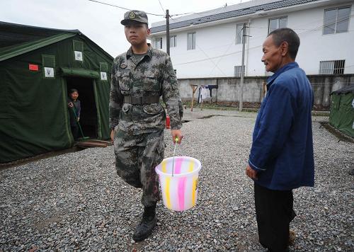 一名戰(zhàn)士在為孤寡老人打水(5月16日攝)。新華社記者 李曉果 攝