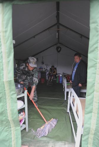 一名戰(zhàn)士在孤寡老人居住的帳篷里拖地(5月16日攝)。新華社記者 李曉果 攝