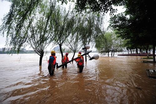 6月10日,廣西柳州市江濱西路被上漲的江水淹沒,路政人員在轉(zhuǎn)移路燈設(shè)施。新華社記者 黃孝邦 攝