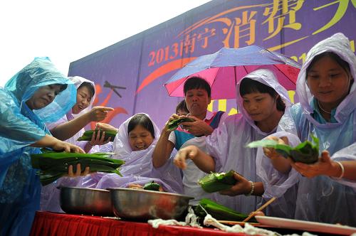 6月10日,市民在“2013年南寧消費(fèi)美食季”開幕式活動(dòng)現(xiàn)場(chǎng)冒雨參加包粽子比賽。當(dāng)日是端午節(jié)小長(zhǎng)假第一天。全國(guó)各地紛紛舉辦各種形式的慶祝紀(jì)念活動(dòng),喜迎端午節(jié)的到來。新華社記者 陸波岸 攝