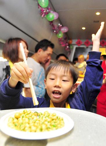 6月10日,在武漢開往宜昌的D5821次列車上,一名小朋友正在參加夾豆子游戲。 新華社記者 肖藝九 攝