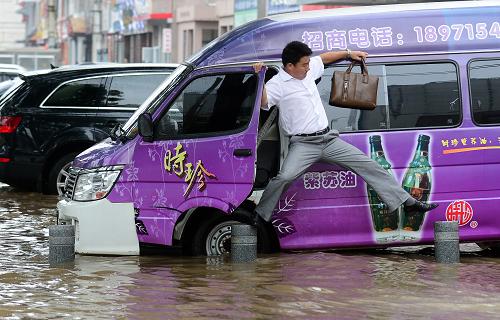 7月7日,一名司機在積水區(qū)停車后艱難下車。新華社記者 程敏 攝