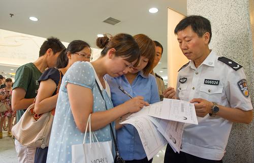 7月13日,重慶市公安局出入境管理局辦證大廳,民警逐個檢查排隊(duì)市民的信息是否有誤,從而節(jié)約辦證時間。新華社記者 陳誠 攝