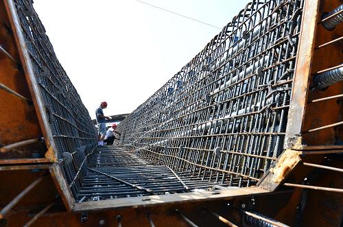 8月3日,在三淅高速公路工地上,兩名工人在捆扎空心梁片的鋼筋。新華社記者 王頌 攝