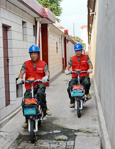 8月16日,黨員供電服務隊的成員騎電動車從一條小巷通過,為一戶居民檢修供電設(shè)備。 新華社記者 楊世堯 攝