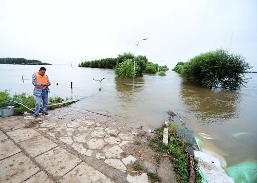 8月19日,在同江市八岔地區(qū),一位民兵在通向江邊廣場的道路上值勤,這條道路已被洪水淹沒。新華社記者 王凱 攝