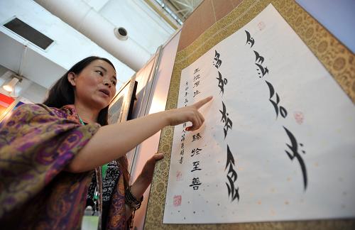 在第四屆中國(guó)桂林國(guó)際旅游博覽會(huì)上,一名來(lái)自湖南省江永縣的女子在推介一幅女書藝術(shù)作品(9月7日攝)。 新華社記者 陸波岸 攝