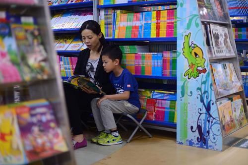 9月13日,在北京西單圖書大廈,孩子在家長的陪同下閱讀少兒讀物。新華社記者 金良快 攝