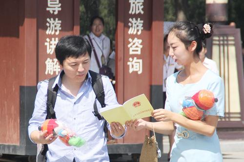 9月13日,西安臨潼華清池景區(qū)服務(wù)人員向游客介紹《中華人民共和國(guó)旅游法》。新華社記者 陳昌奇 攝