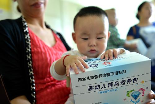 9月18日,家長帶著孩子在湖北省宣恩縣婦幼保健院領(lǐng)取免費“營養(yǎng)包”。 新華社發(fā)(宋文 攝)