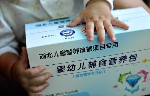 9月18日,在湖北省宣恩縣婦幼保健院的免費“營養(yǎng)包”發(fā)放點,一個兒童在擺弄剛領(lǐng)到的“營養(yǎng)包”。 新華社發(fā)(宋文 攝)
