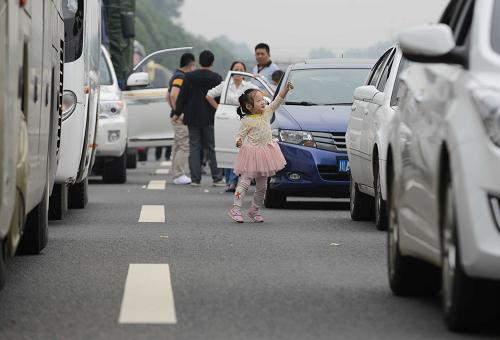 10月1日,在成雅高速擁堵路段,一名小朋友在等待通車時玩耍。當(dāng)日是今年“十一”黃金周高速公路小客車免費通行第一天,四川境內(nèi)成雅、雅西、成綿等多條高速擁堵。四川省高速交警預(yù)計出行高峰時間為今明兩天,返程高峰為6至7日,車流將集中在成雅、雅西、成綿、成渝、成樂等高速路段。新華社記者 李橋橋 攝