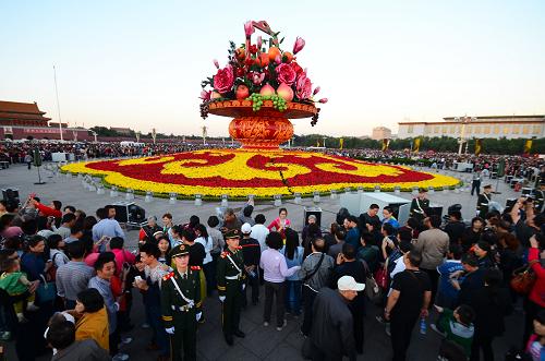 10月1日,游客在天安門廣場(chǎng)觀看國(guó)慶巨型花籃。