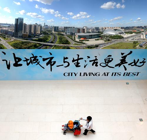 積極推進(jìn)城鎮(zhèn)化建設(shè),城市生活更美好。上圖:沈陽渾南地區(qū)景色(2013年8月30日攝)。下圖:2012年9月28日,市民路過沈陽市府恒隆廣場的宣傳板。新華社記者 李鋼 攝