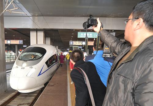 12月1日,旅客在天津西站的首列G420次高鐵列車前拍照留念。當(dāng)日上午9點51分,首列G420次高鐵列車駛出天津西站,津秦高速鐵路正式開通運營。津秦高鐵運營里程為287公里,設(shè)計時速350公里,起點為天津西站,終點為秦皇島站。全線設(shè)天津、唐山、北戴河和秦皇島等9個車站,津秦兩地間最快鐵路交通時間由兩個多小時壓縮至1小時11分。津秦高鐵的開通將東北、華北、華東地區(qū)的快速客運通道連接成網(wǎng),大大縮短了東北到關(guān)內(nèi)地區(qū)的鐵路交通時間。新華社記者 岳月偉 攝