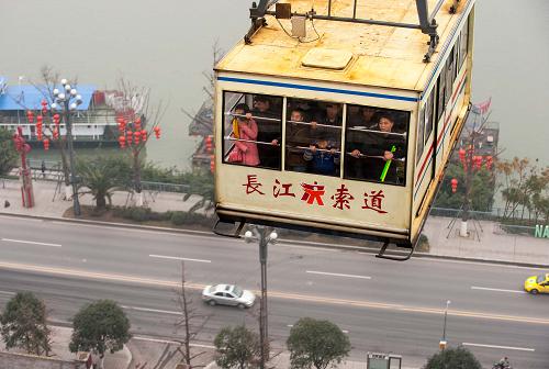 1月1日,前來體驗的重慶市民和外地游客站在索道車廂的窗戶前觀看窗外長江兩岸的風景。當日,重慶長江索道完成電氣系統(tǒng)更新工程后變身景區(qū)正式投入試運營。其主要承擔功能將逐步由交通功能轉變?yōu)槁糜斡^光,試運營期間白天運行暫不調慢速度,仍然為每秒6米,但晚上的速度減到每秒3米,便于人們觀看夜景。長江索道建于1987年,全長1166米,年均載客量超過300萬人次。新華社記者 劉潺 攝