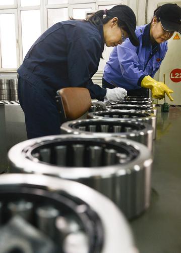 在烏魯木齊鐵路局車輛段檢修區(qū),兩名鐵路工人在對(duì)車輪軸承進(jìn)行檢查編號(hào)(1月14日攝)。新華社記者 王菲 攝