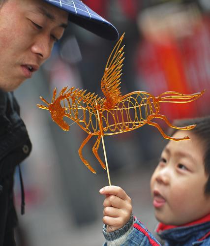 在長(zhǎng)沙坡子街,一名男孩手舉著剛剛從廟會(huì)上買(mǎi)的糖畫(huà)(2月3日攝)。2014年春節(jié),美味價(jià)廉的傳統(tǒng)小吃更多地占據(jù)老百姓的春節(jié)味蕾。家鄉(xiāng)街頭巷尾傳統(tǒng)小吃的味道,寄托著游子對(duì)故鄉(xiāng)的思念,承載著老百姓對(duì)傳統(tǒng)春節(jié)樸素而又溫暖的記憶。新華社記者 李尕 攝