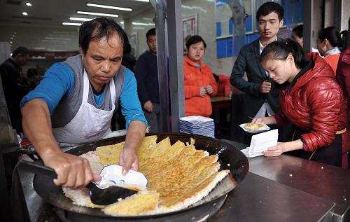 長(zhǎng)沙坡子街一家小吃店的工作人員正在制作長(zhǎng)沙當(dāng)?shù)匦〕?#8212;—長(zhǎng)沙豆皮(2月2日攝)。 新華社記者 李尕 攝