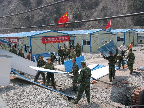 7月8日,部隊官兵在現(xiàn)場施工。連日來,在“5·12”特大地震震中區(qū)域汶川縣映秀鎮(zhèn),部隊官兵及來自廣東等地的援建施工人員冒著酷熱,加緊建設(shè)過渡板房。 新華社記者 任會斌 攝