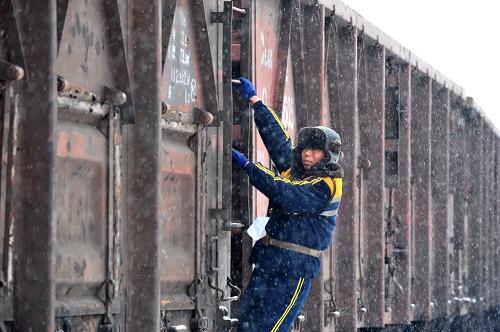 11月16日,鐵路職工在西安西站編組場(chǎng)冒雪進(jìn)行調(diào)車(chē)作業(yè)。 新華社發(fā)(唐振江 攝)