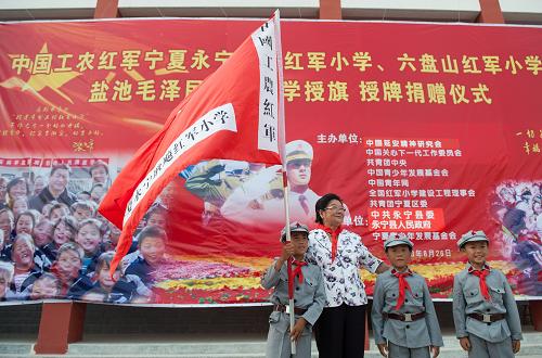 8月26日,中國關(guān)心下一代工作委員會主任顧秀蓮向永寧耿飚紅軍小學(xué)的同學(xué)們授旗。 新華社記者李琰攝