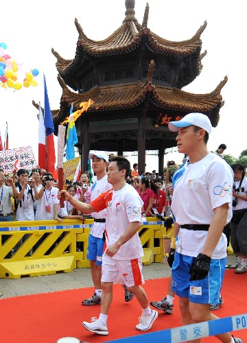 奧運(yùn)圣火在武漢傳遞 5月31日,奧運(yùn)火炬手楊威(中)手持火炬?zhèn)鬟f。當(dāng)日,北京奧運(yùn)圣火在湖北武漢傳遞。 新華社記者程敏攝