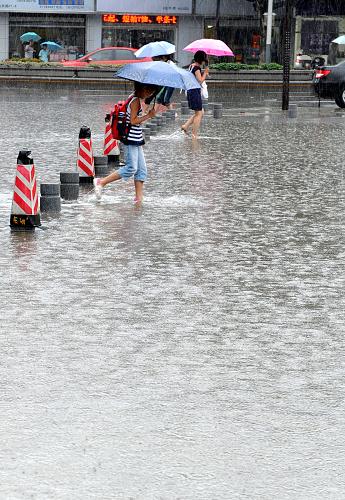 7月12日,南京新街口,市民冒雨趟過(guò)一處積水的道路。近日,江蘇省出現(xiàn)大范圍連續(xù)性強(qiáng)降雨,省氣象臺(tái)發(fā)布暴雨警報(bào),并稱(chēng)未來(lái)幾天強(qiáng)降雨仍將持續(xù),提醒有關(guān)部門(mén)防范降雨可能造成的各種災(zāi)害。新華社記者 孫參 攝