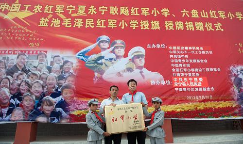 8月26日,全國紅軍小學(xué)建設(shè)工程理事會秘書長方強(右二)向永寧耿飚紅軍小學(xué)授校牌。 新華社記者李琰攝