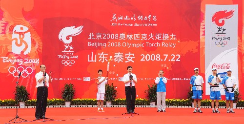 7月22日,第一棒火炬手邢傲偉(左二)在起跑儀式上高舉火炬。當日,北京奧運圣火在山東省泰安市傳遞。 新華社記者 劉力航 攝