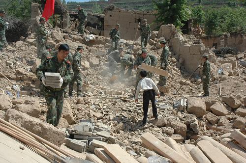 2008年5月16日,解放軍戰(zhàn)士在甘肅隴南市武都區(qū)馬街鎮(zhèn)蒿坪村幫助村民清掃廢墟。