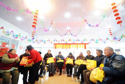 1月25日是農(nóng)歷除夕,在四川地震重災(zāi)區(qū)綿竹市劍南鎮(zhèn)紫巖社區(qū)板房敬老院,有關(guān)方面領(lǐng)導(dǎo)在向因地震致孤致殘的老年人贈(zèng)送禮品。 新華社記者 李曉果 攝