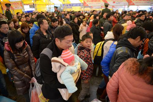 2月14日,一名抱著孩子的旅客正隨著人群進站上車。新華社記者 周密 攝