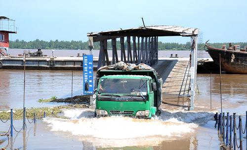 7月25日,在長江江西九江段碼頭,貨車在積水中前行。新華社發(fā)(胡國林 攝)