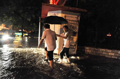 7月30日,在寧夏銀川城區(qū)內,兩位路人在冒雨從水中走過。新華社記者 彭昭之 攝