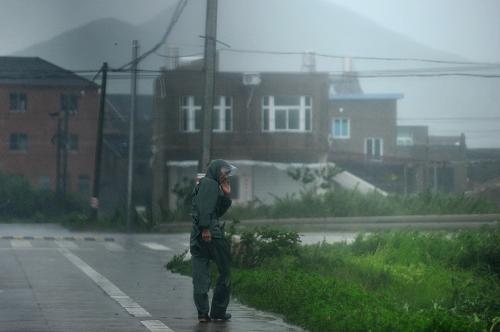 8月8日,浙江省象山縣鶴浦鎮(zhèn)的一位行人在狂風(fēng)中艱難前行。 新華社記者 黃宗治 攝