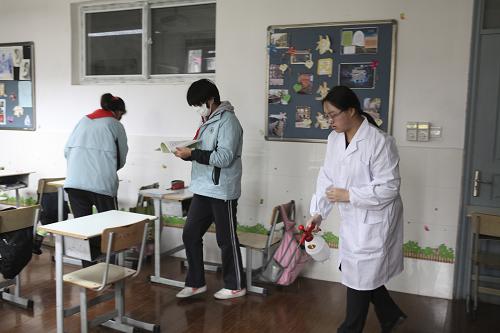 12月9日,上海市長(zhǎng)寧區(qū)省吾中學(xué)校醫(yī)在教室里噴灑消毒液殺菌。新華社發(fā)(朱水苗 攝)