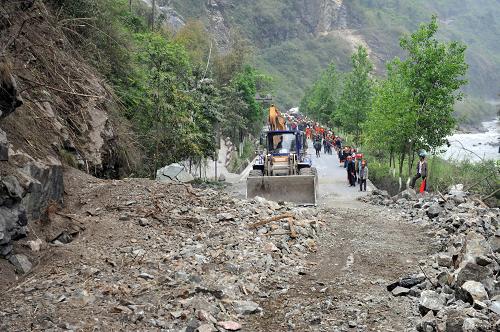 4月21日,在通往寶興縣的210省道上,一臺大型推土機(jī)在清理公路路面上的碎石堆。新華社社記者劉潺攝