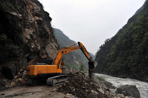 4月21日,在通往寶興縣的210省道上,一臺大型挖掘機(jī)在清理公路路面上的碎石堆。新華社社記者劉潺攝