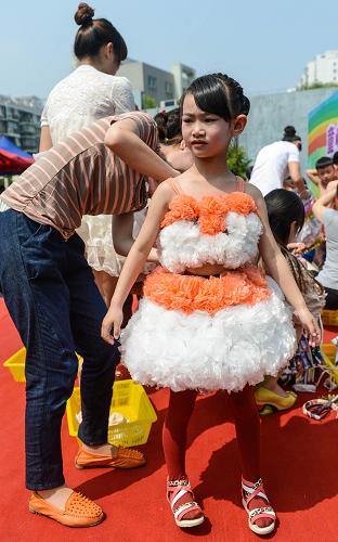 5月21日,媽媽幫助孩子穿上用廢舊桌布、塑料袋做成的環(huán)保時裝。新華社記者 徐昱 攝