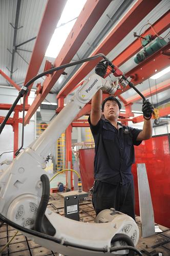5月21日,在河北省南皮縣一家機電產(chǎn)品制造企業(yè),工人在調(diào)試焊接機器人。新華社記者王民