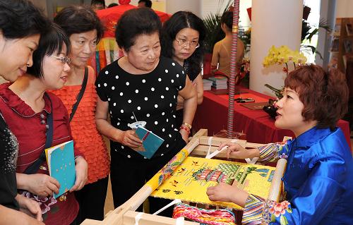 5月28日,武漢漢繡第五代傳人任煒(右一)在為苗栗縣的民眾介紹漢繡工藝。當(dāng)日,為期3天的“武漢民俗文化展”在臺(tái)灣苗栗縣舉行。來(lái)自武漢的16類(lèi)300余件民間藝術(shù)作品亮相,8位民間工藝家現(xiàn)場(chǎng)展示技藝并與觀眾互動(dòng),讓當(dāng)?shù)孛癖姼惺芪錆h民俗文化的魅力。新華社記者陶明攝