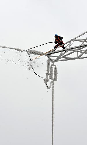 2月9日,電力工人在供電塔上破除覆冰。新華社發(fā)(鄭家裕 攝)