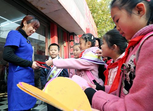 11月16日,濟(jì)南市芙蓉小學(xué)的學(xué)生在向“綠色通道”兩邊商家發(fā)送自己制作交通安全提示卡。新華社記者 朱崢 攝