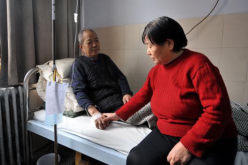 11月21日,在山西省運(yùn)城市中心醫(yī)院,胡丙申的妻子王金梅為丈夫活動(dòng)手腕。記者從山西省運(yùn)城市中心醫(yī)院了解到,備受社會(huì)關(guān)注的“還債局長(zhǎng)”胡丙申因患肺癌晚期住進(jìn)該院接受治療,目前病情基本穩(wěn)定,但身體虛弱不適合化療。胡丙申,山西夏縣人,在擔(dān)任山西夏縣鄉(xiāng)鎮(zhèn)企業(yè)局局長(zhǎng)期間,為了幫助當(dāng)?shù)匕l(fā)展鄉(xiāng)鎮(zhèn)企業(yè),以個(gè)人名義先后為19戶(hù)農(nóng)民擔(dān)保借貸69萬(wàn)多元資金,后因?yàn)椴糠洲r(nóng)民破產(chǎn)無(wú)法還債,胡丙申自己背上了39萬(wàn)元債務(wù)。退休后,胡丙申沒(méi)有逃避,而是毅然選擇打工還債。10年間,他擺過(guò)地?cái)傎u(mài)對(duì)聯(lián)、賣(mài)鞭炮,開(kāi)過(guò)飯館、理發(fā)店,搞過(guò)養(yǎng)生館,經(jīng)營(yíng)過(guò)小商店,甚至給人做飯、剃頭......終于在2010年元旦還完了最后一筆債務(wù)。2011年9月份,胡丙申正式結(jié)束打工生活,回到夏縣老家安享晚年,兩個(gè)多月后檢查出患上肺癌。胡丙申接受肺癌治療后,運(yùn)城市和夏縣的地方領(lǐng)導(dǎo)紛紛前往慰問(wèn),為其捐款,夏縣的多個(gè)政府部門(mén)也主動(dòng)為胡丙申捐款。在網(wǎng)絡(luò)上,“還債局長(zhǎng)”胡丙申因肺癌晚期住院的消息也引起了網(wǎng)民們的關(guān)注。許多網(wǎng)友通過(guò)微博紛紛獻(xiàn)上祝福,并呼吁大家為其募捐治療所需的費(fèi)用。