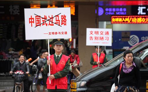 12月1日,廣東邊防七支隊(duì)官兵在深圳市繁華路段的十字路口舉著標(biāo)語(yǔ),倡導(dǎo)市民文明過(guò)馬路。新華社發(fā)(廖鍵 攝)